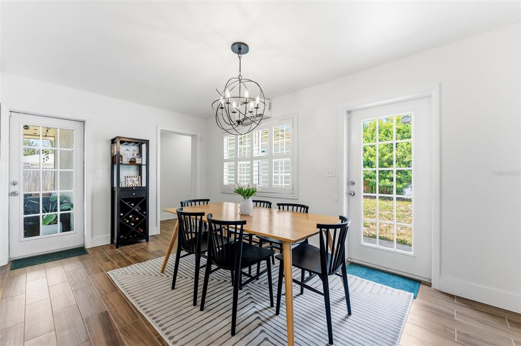 A dining room features a wooden table, black chairs, a chandelier, and two glass doors — 3905 W PEARL AVENUE, TAMPA, FL