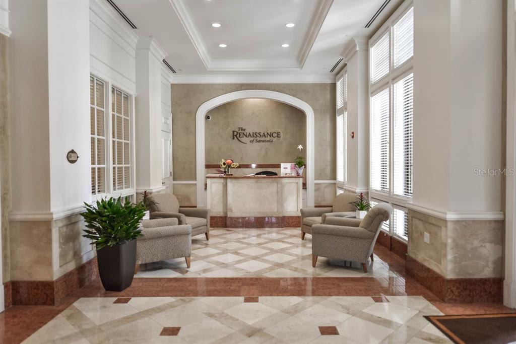 A lobby with a reception desk, patterned tile floors, and seating areas under an archway — 750 N TAMIAMI TRAIL UNIT 1007, SARASOTA, FL