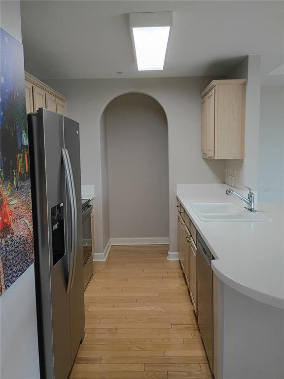 A kitchen features light wood cabinets, white countertops, stainless steel appliances, and an arched alcove — 750 N TAMIAMI TRAIL UNIT 1007, SARASOTA, FL