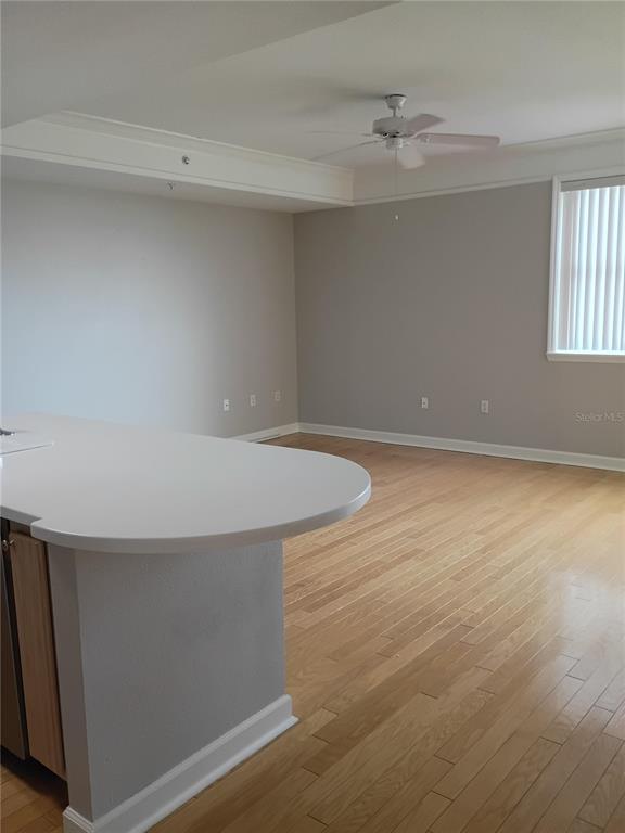 A kitchen island with a white countertop overlooks a room with hardwood floors and ceiling — 750 N TAMIAMI TRAIL UNIT 1007, SARASOTA, FL