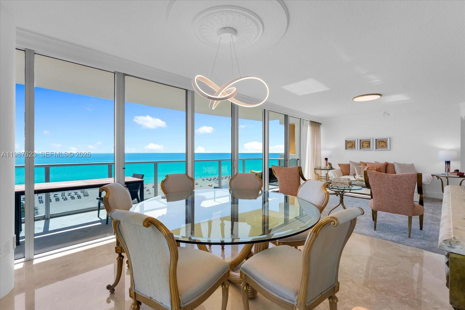 A dining area with a glass table and ocean views through floor-to-ceiling windows — 1455 Ocean Dr # 909, Miami Beach FL 33139, MIAMI BEACH, FL