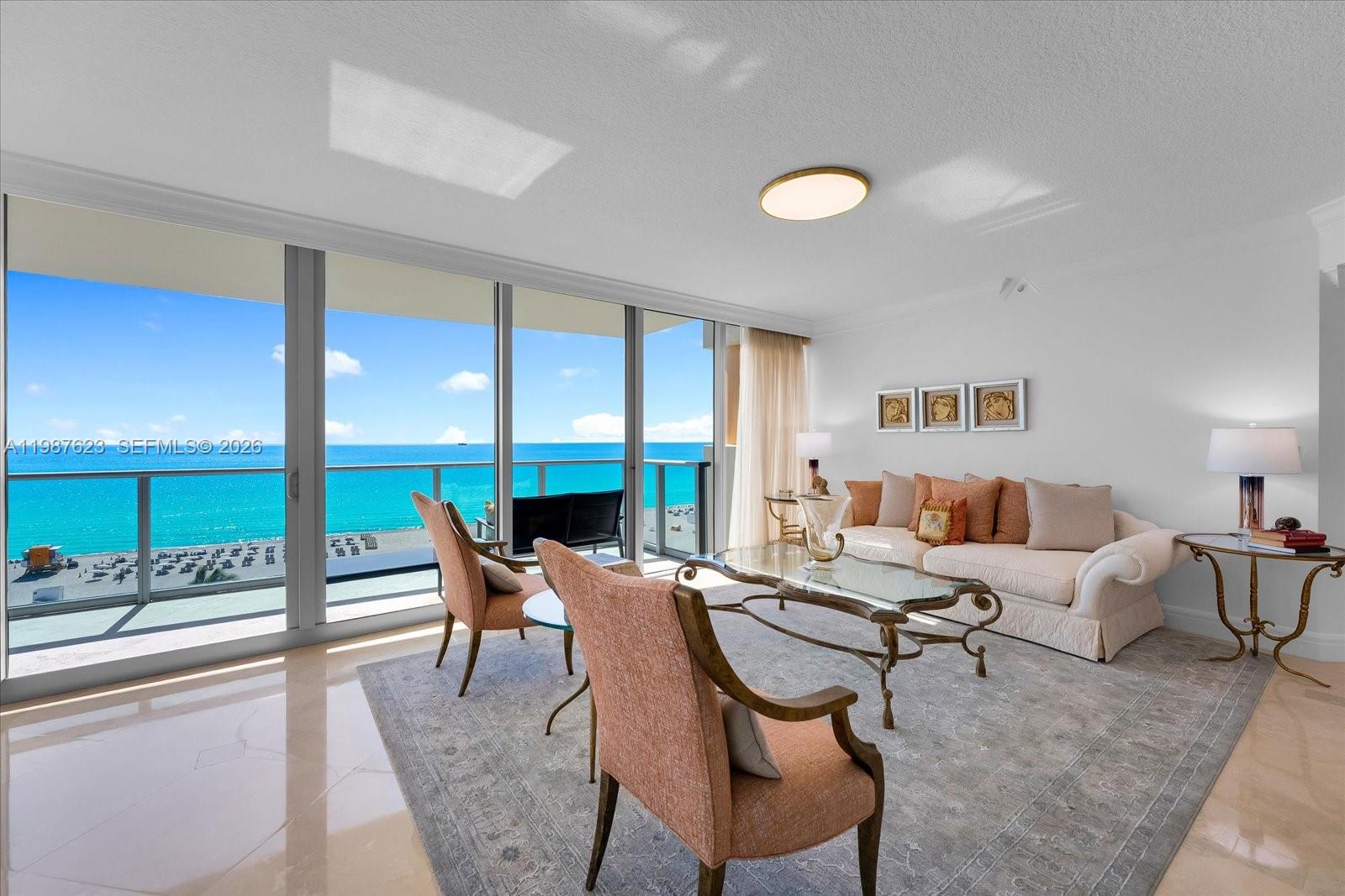 A living room features a beige sofa, two armchairs, and floor-to-ceiling windows overlooking the ocean — 1455 Ocean Dr # 909, Miami Beach FL 33139, MIAMI BEACH, FL