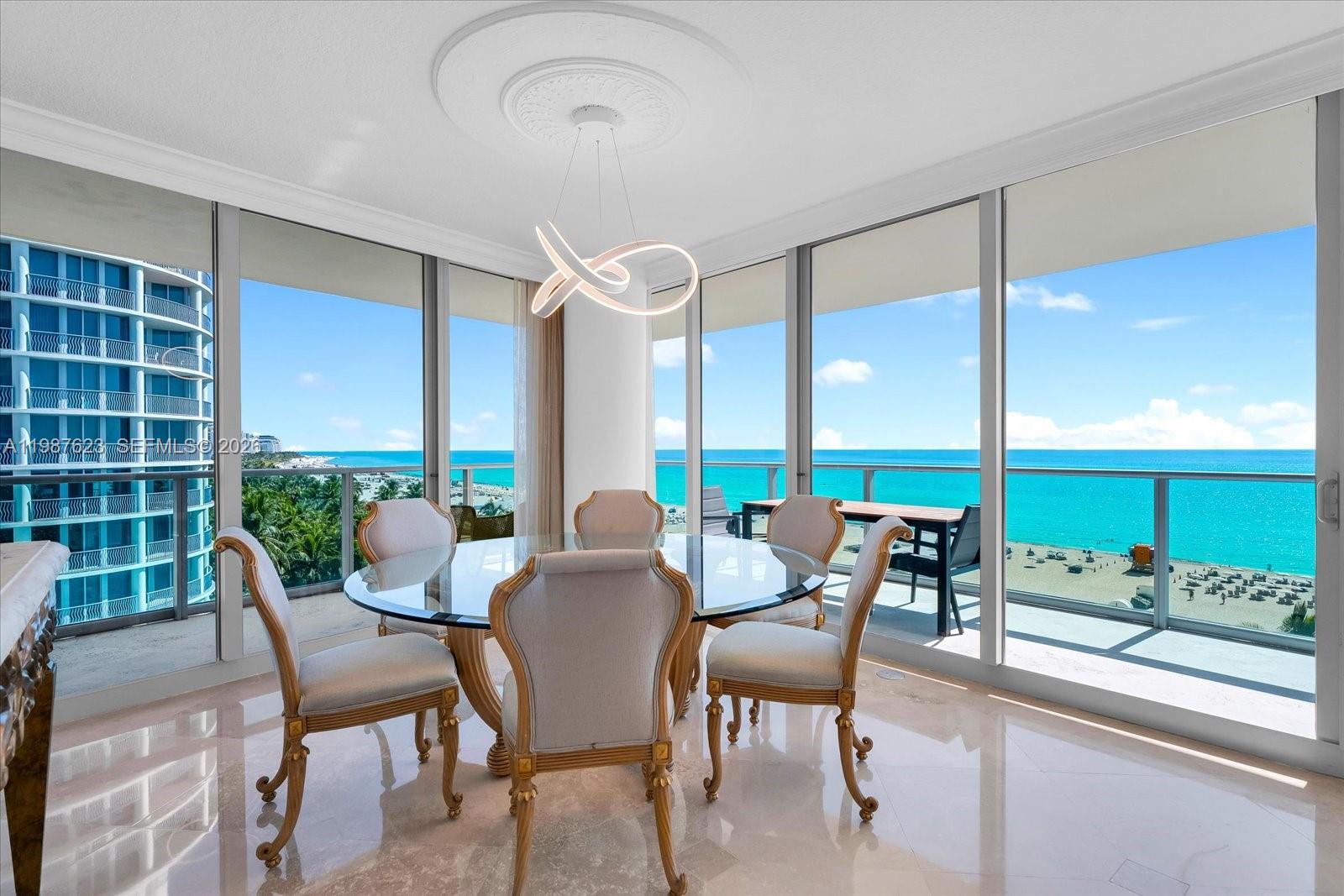 A dining room with a glass table and ocean views through floor-to-ceiling windows — 1455 Ocean Dr # 909, Miami Beach FL 33139, MIAMI BEACH, FL