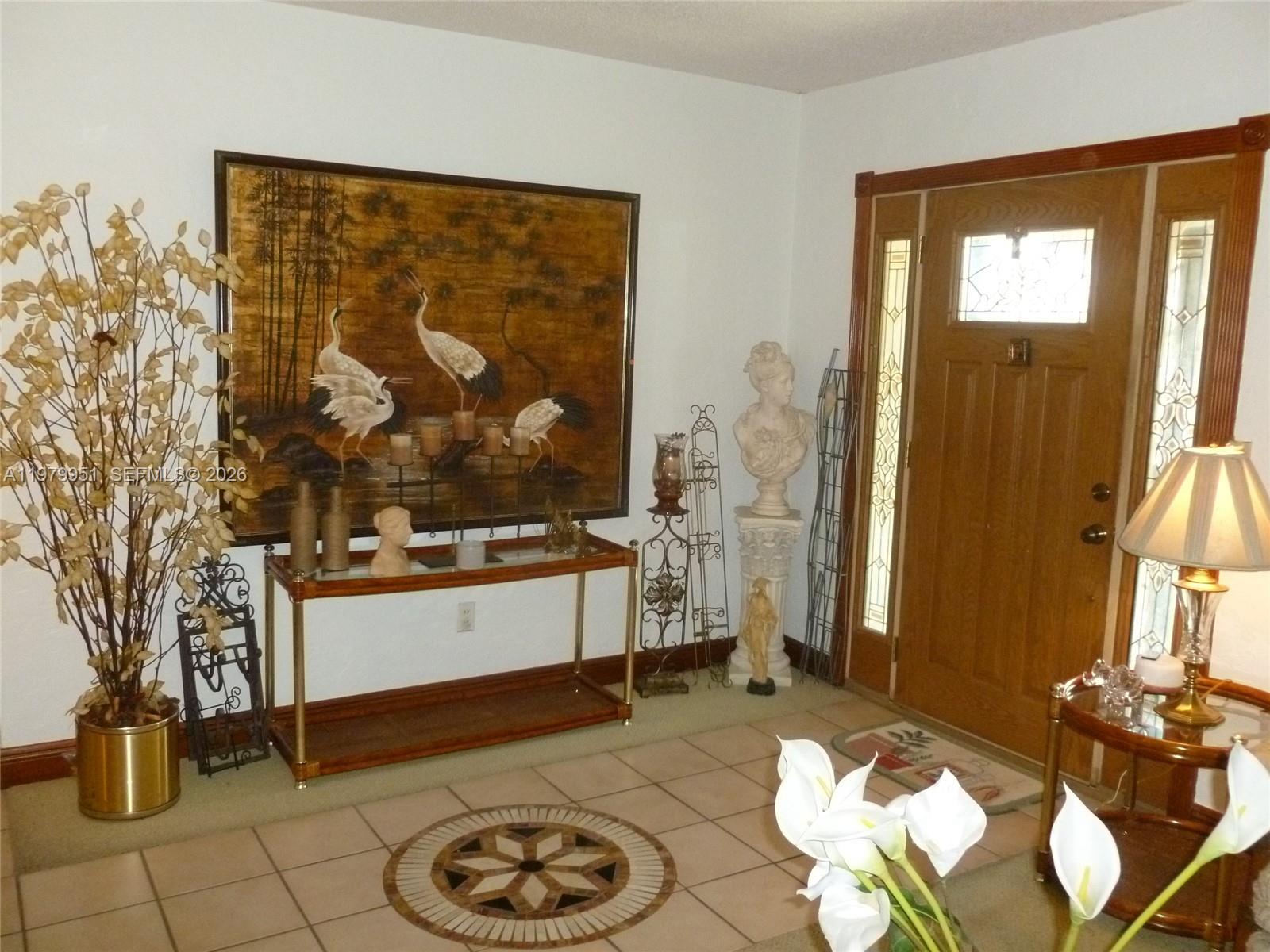 An entryway features a tiled floor with a medallion, a console table, and a wooden door — 3261 NW 14th St, Miami FL 33125, MIAMI, FL