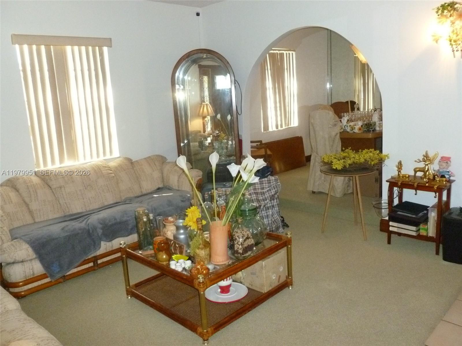 A living room features a beige sofa, a glass coffee table, and an arched entryway — 3261 NW 14th St, Miami FL 33125, MIAMI, FL