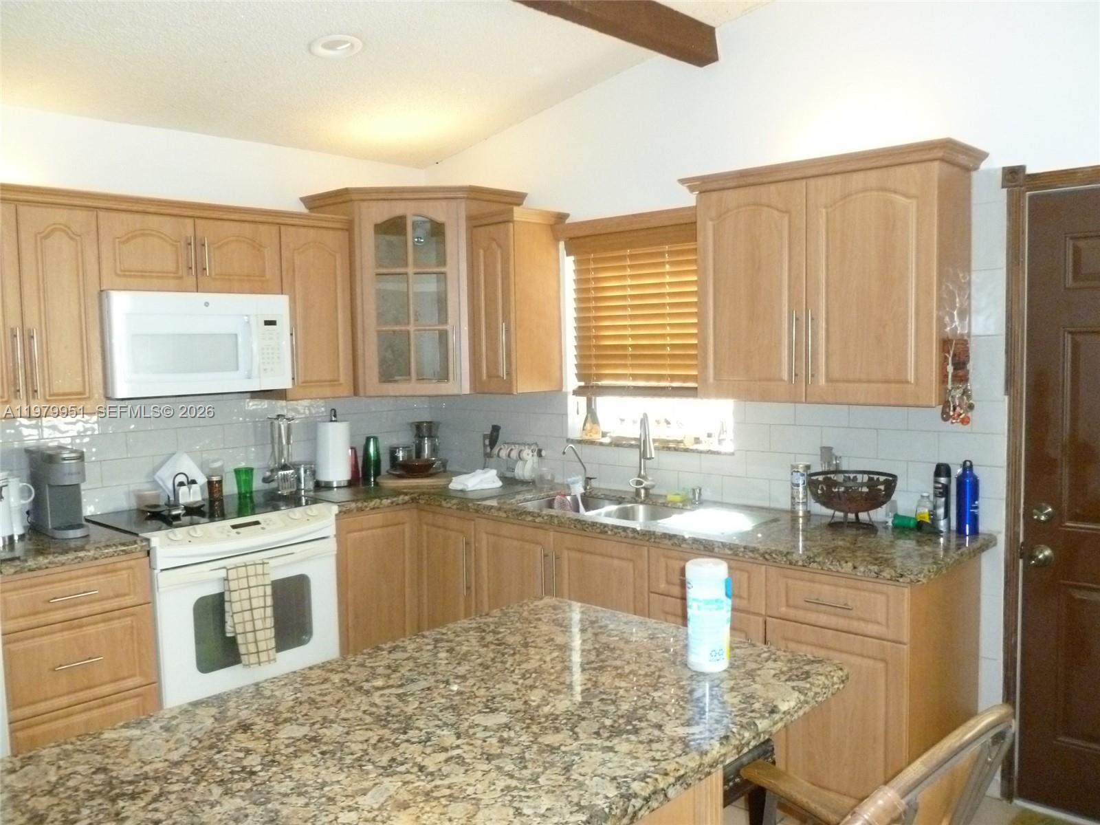 A kitchen features light wood cabinets, granite countertops, a white stove, and a central island — 3261 NW 14th St, Miami FL 33125, MIAMI, FL