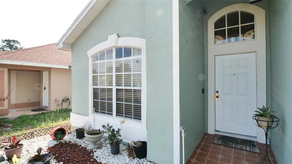 A two-story house with light green stucco and siding features a white garage door — 4381 CREEKSIDE BOULEVARD, KISSIMMEE, FL