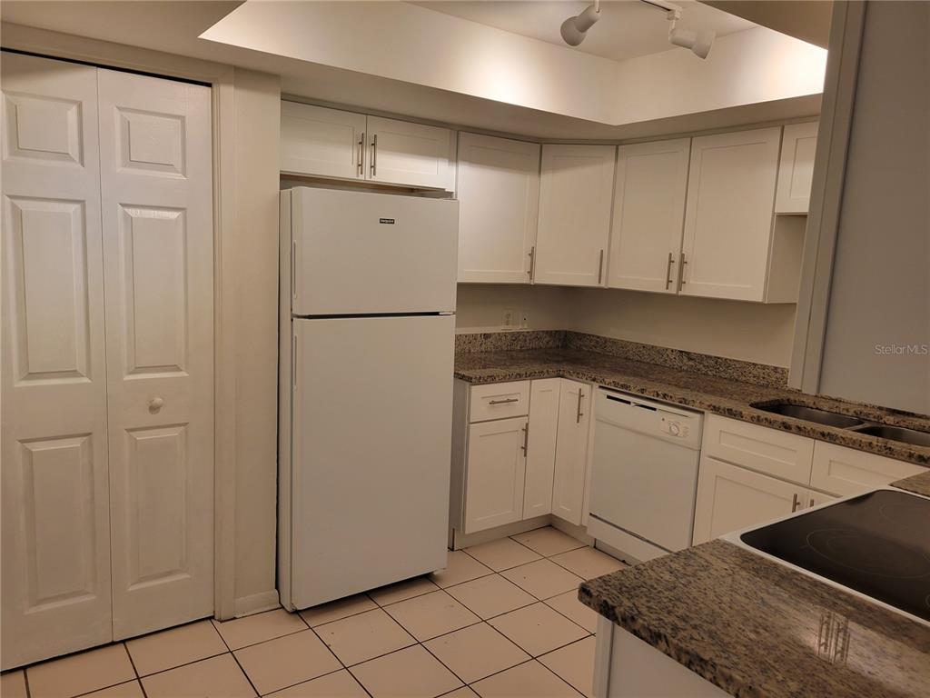 A kitchen features white cabinets, a white refrigerator, a dishwasher, and speckled granite countertops — 1508 N SATURN AVENUE, CLEARWATER, FL
