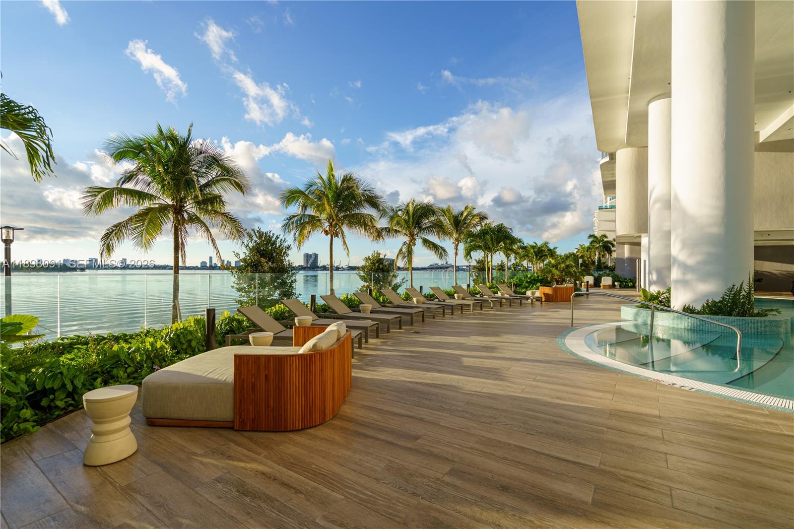 A poolside deck features lounge chairs, palm trees, and a view of the water — 700 NE 24th St # 4002, Miami FL 33137, MIAMI, FL