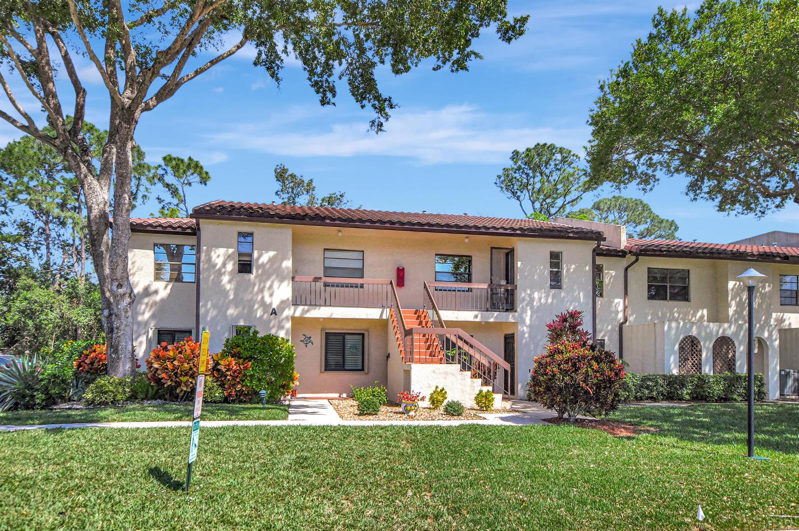 A two-story apartment building with a central staircase, stucco exterior, and surrounding landscaping — 21864 Arriba Real # 3d, Boca Raton FL 33433, BOCA RATON, FL