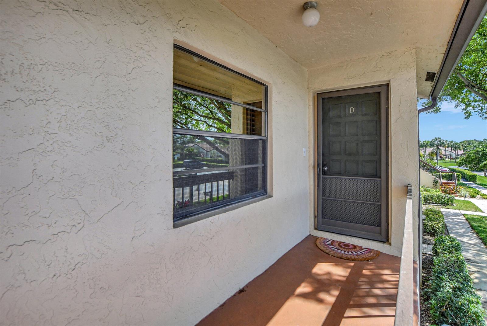 An exterior view of a building entrance with a brown door labeled D and window — 21864 Arriba Real # 3d, Boca Raton FL 33433, BOCA RATON, FL