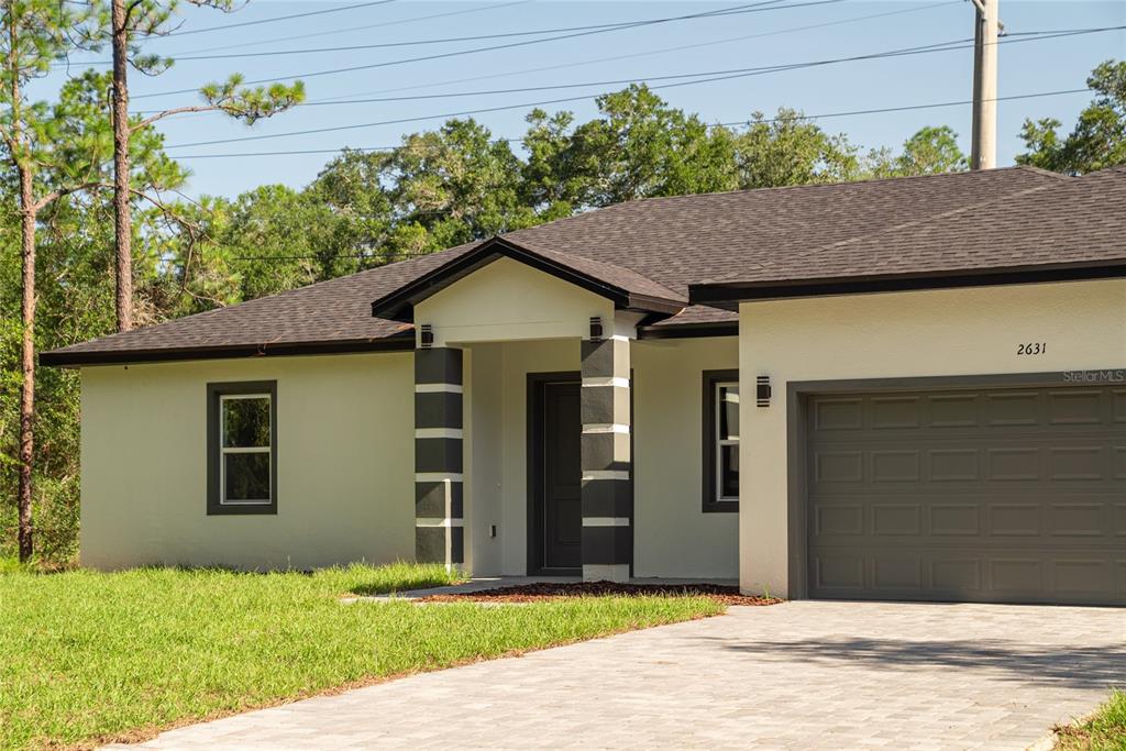 A single-story house with a light-colored stucco exterior, dark roof, and a paved driveway — 2631 W ROYAL PALM DRIVE, CITRUS SPRINGS, FL