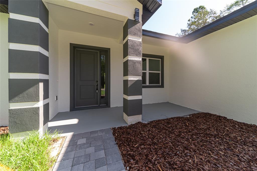 A front entryway features a dark gray door, two stone-accented columns, and a paved walkway — 2631 W ROYAL PALM DRIVE, CITRUS SPRINGS, FL
