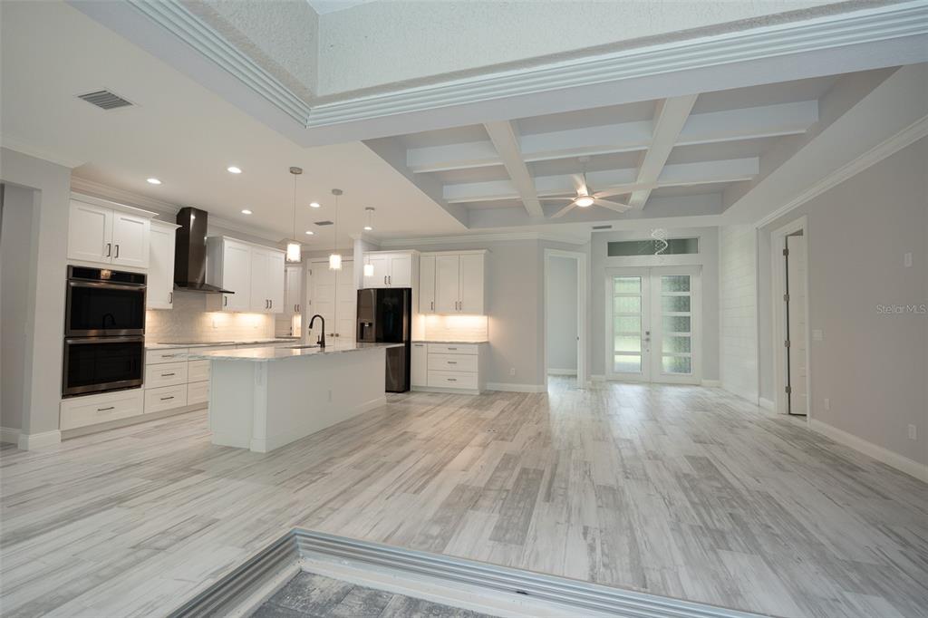 A modern kitchen with white cabinetry, a center island, and wood-look tile flooring — 140 SNOWDEN STREET, PORT CHARLOTTE, FL
