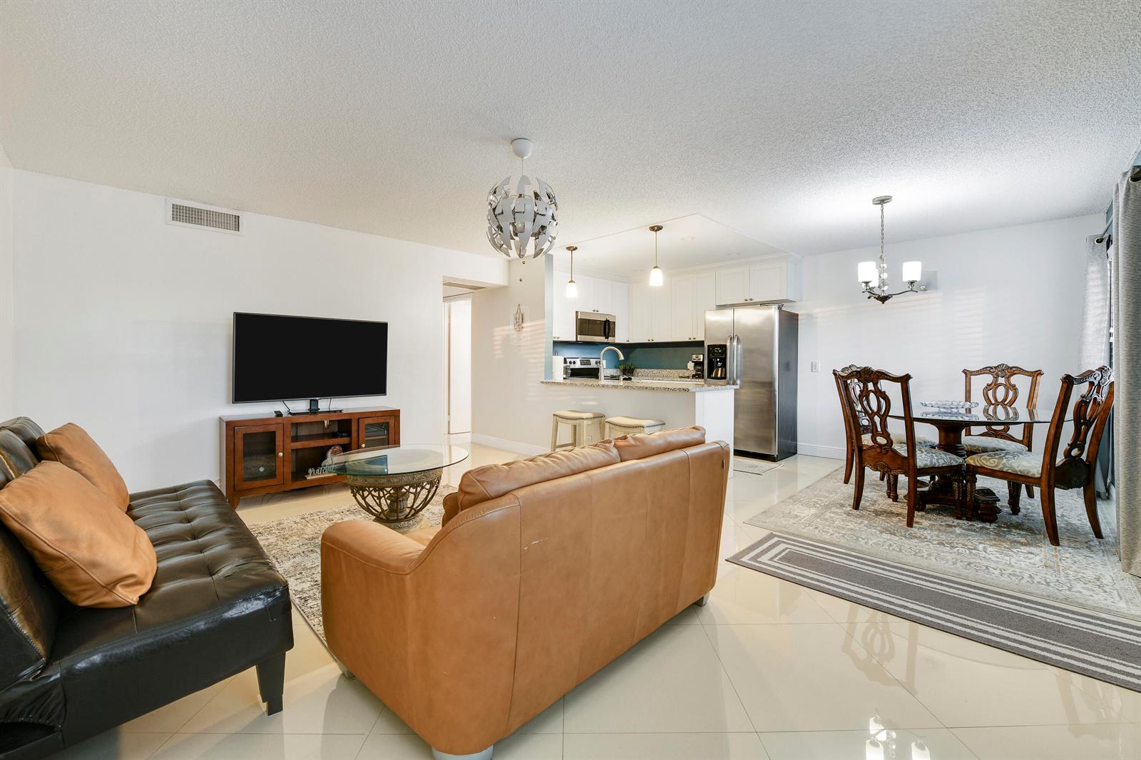 An open-concept living and dining area with a kitchen, tile flooring, and neutral walls — 3100 Springdale Boulevard # 314, Palm Springs FL 33461, PALM SPRINGS, FL