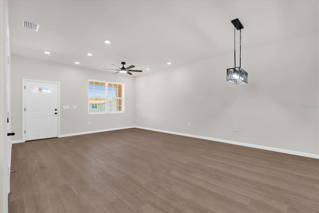 An empty room with light gray walls, wood-look flooring, a ceiling fan, and a pendant light — 1807 PEACH AVENUE, SANFORD, FL