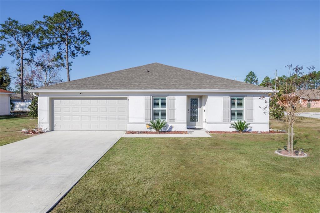 A single-story house with a white stucco exterior, a two-car garage, and a shingled roof — 2 RAINROCK PLACE, PALM COAST, FL