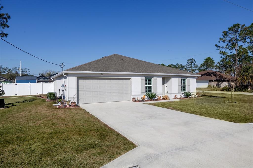 A single-story house with a white exterior, a two-car garage, and a concrete driveway — 2 RAINROCK PLACE, PALM COAST, FL