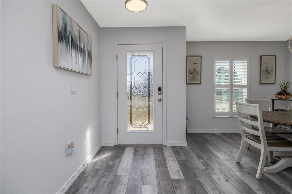 A bright entryway features gray wood-look flooring, a white front door, and a dining area — 2 RAINROCK PLACE, PALM COAST, FL