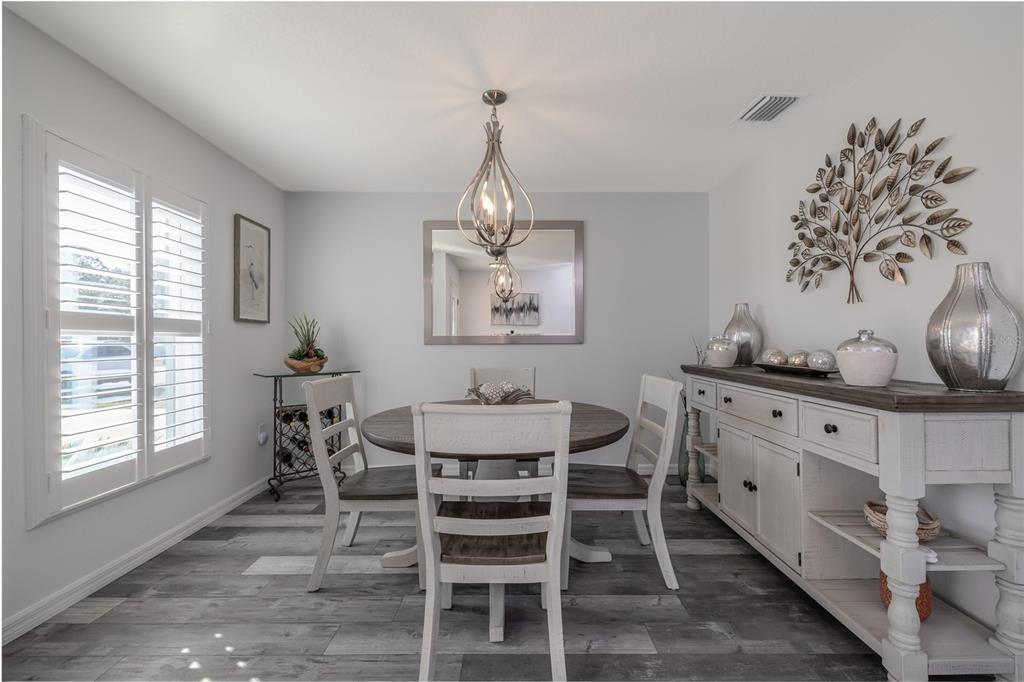 A dining room with a round wooden table, white chairs, and a matching sideboard — 2 RAINROCK PLACE, PALM COAST, FL