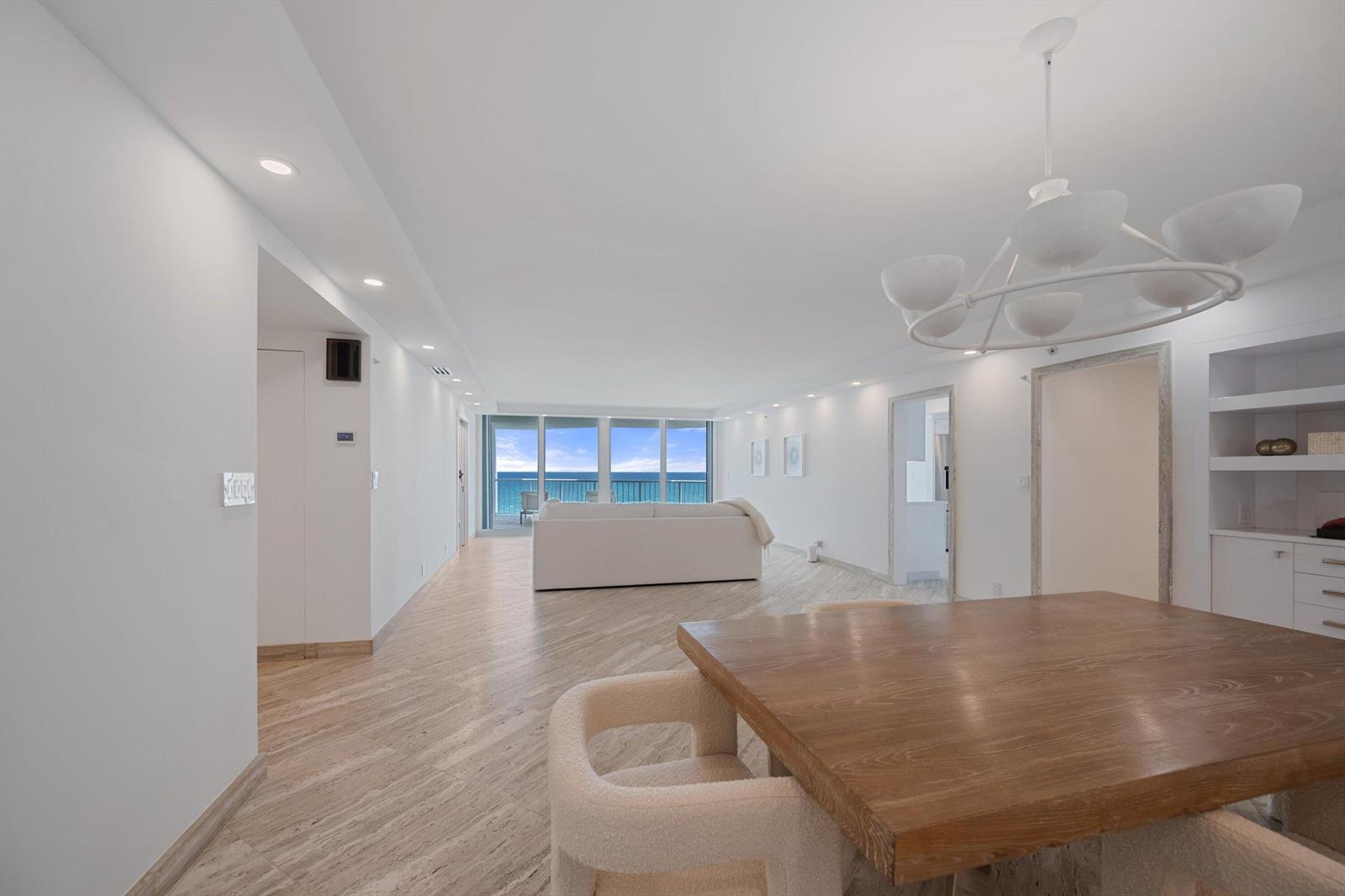 A bright, open-concept living and dining area features light wood-look flooring and ocean views — 3170 S Ocean Boulevard # 601n, Palm Beach FL 33480, PALM BEACH, FL