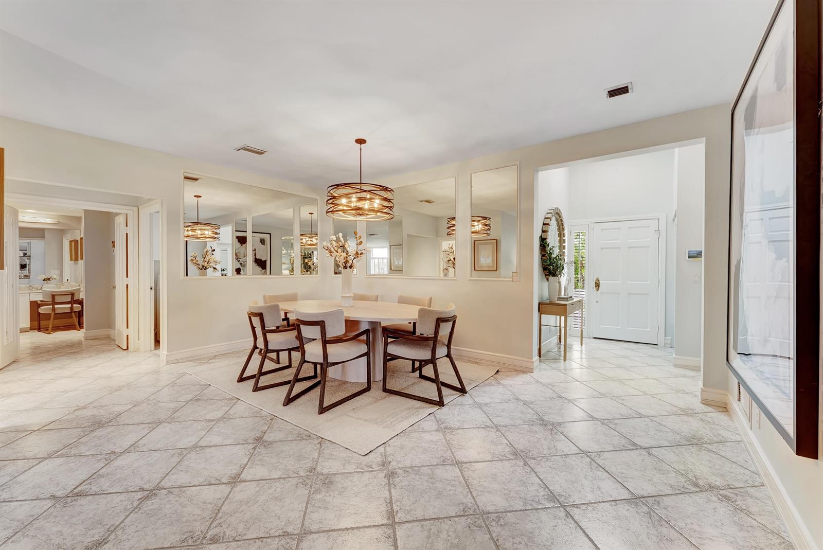 A dining room features a round table, modern chairs, a chandelier, and wall-mounted mirrors — 310 Spyglass Way, Jupiter FL 33477, JUPITER, FL