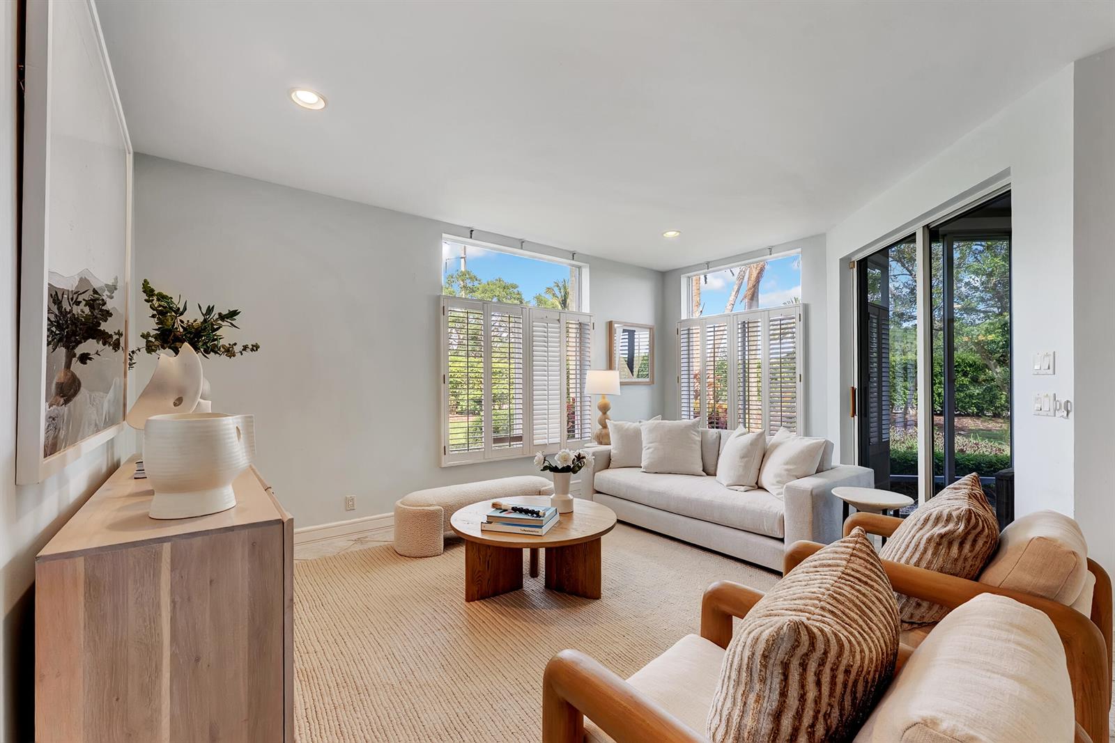 A bright living room features a beige sofa, two wooden armchairs, and large shuttered windows — 310 Spyglass Way, Jupiter FL 33477, JUPITER, FL