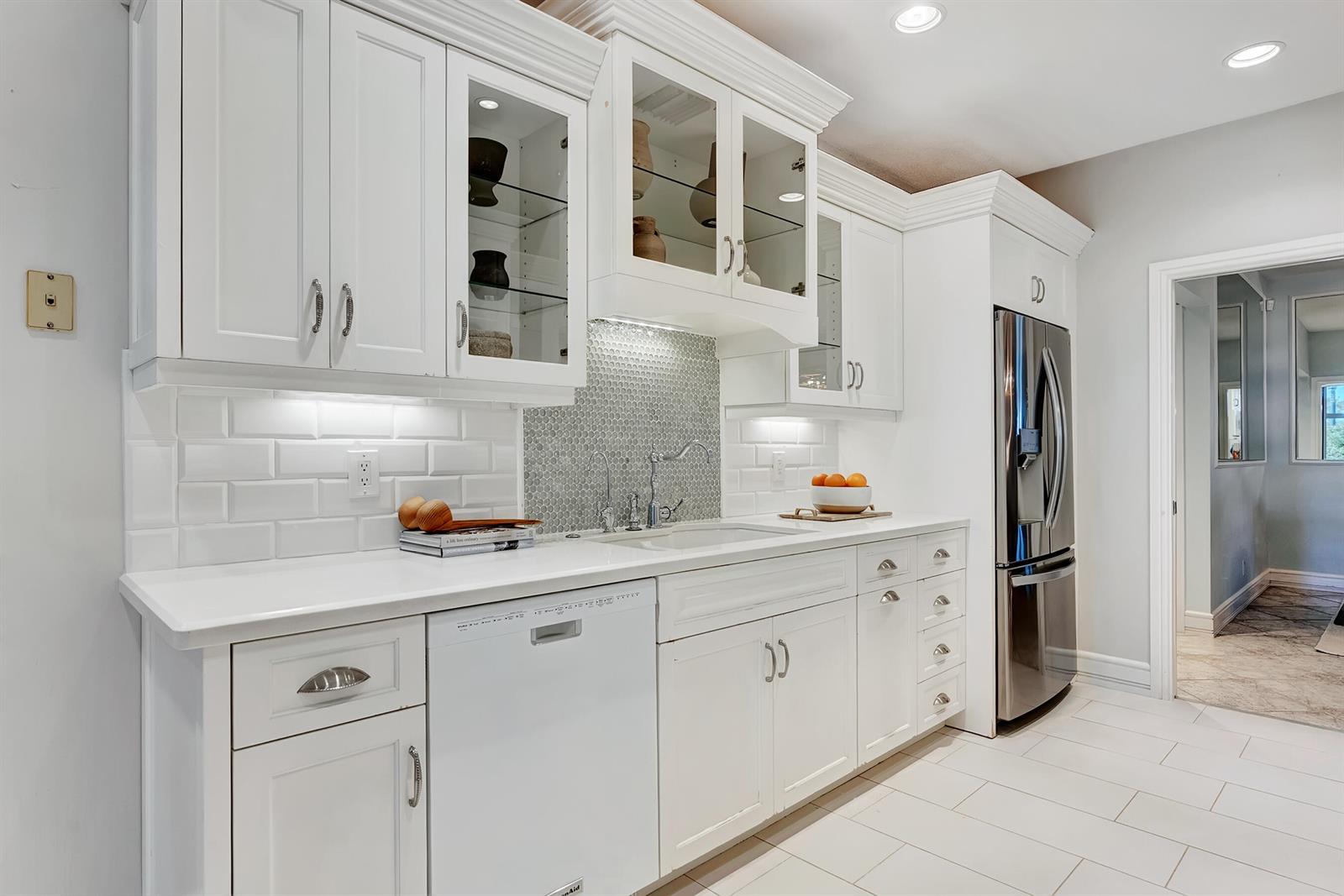 A bright kitchen features white cabinetry, a subway tile backsplash, and stainless steel appliances — 310 Spyglass Way, Jupiter FL 33477, JUPITER, FL