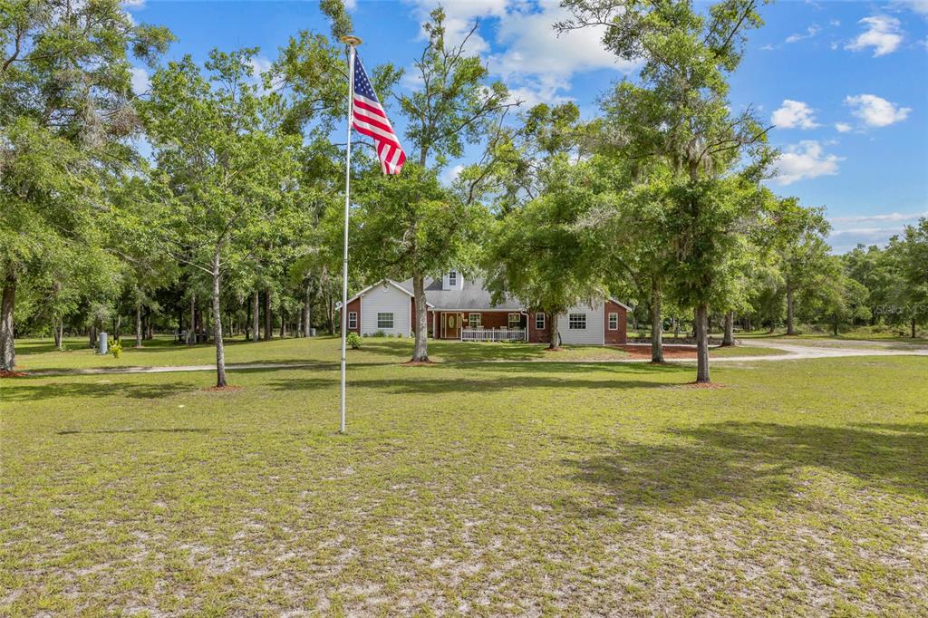 A single-story house with a flag pole in the foreground sits on a grassy lot — 1827 SW SHILOH STREET, FORT WHITE, FL