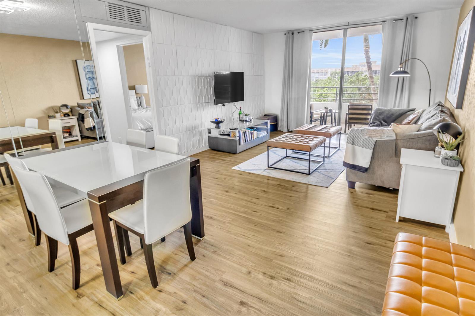 A living and dining area features wood-look flooring, a textured accent wall, and a balcony — 500 Three Islands Boulevard # 109, Hallandale Beach FL 33009, HALLANDALE BEACH, FL