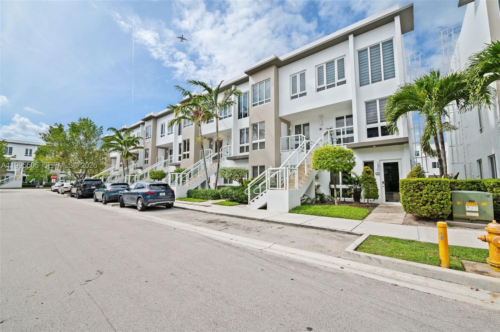 A row of modern white townhomes with exterior staircases and parked cars on the street — 10305 NW 63rd Ter # 105, Doral FL 33178, DORAL, FL