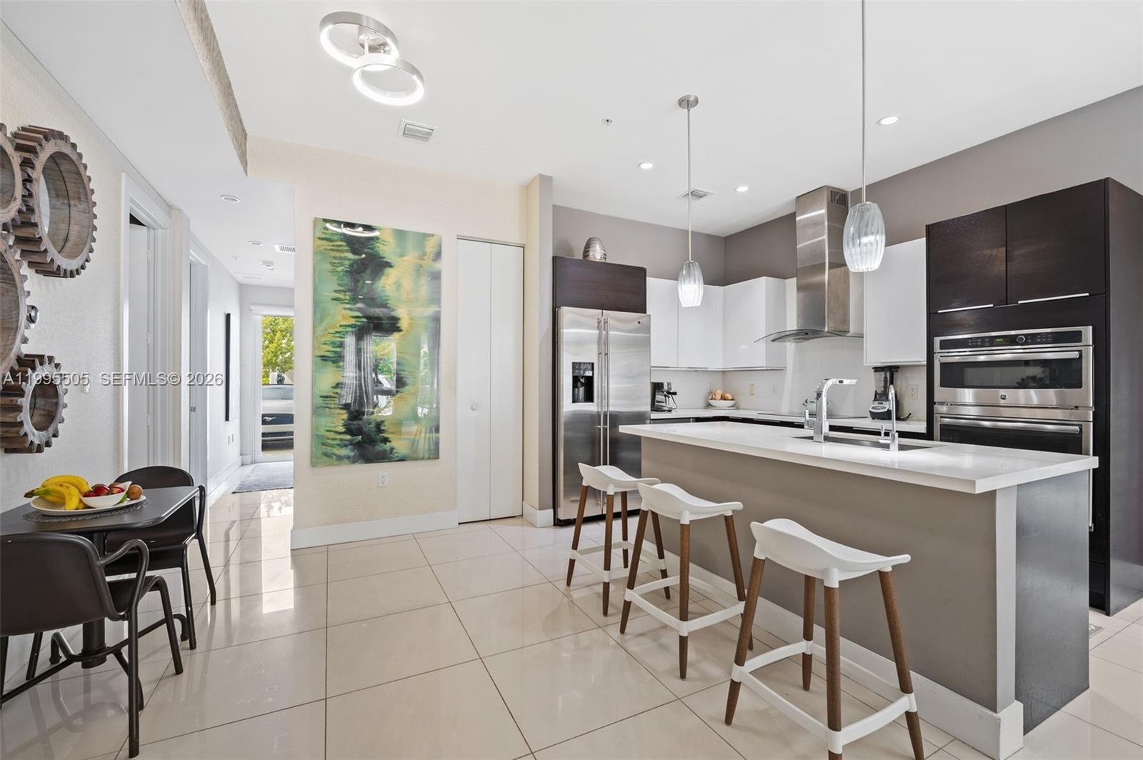 A modern kitchen features white cabinets, stainless steel appliances, a breakfast bar, and tile flooring — 10305 NW 63rd Ter # 105, Doral FL 33178, DORAL, FL