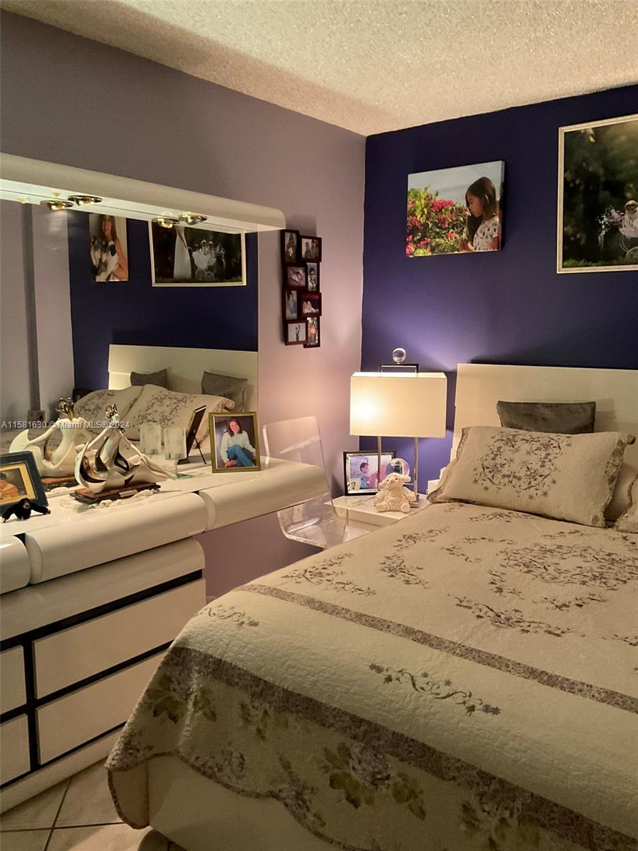 A bedroom features a white bed, a matching dresser with a mirror, and dark-painted walls — 4675 W 18th Ct # 502, Hialeah FL 33012, HIALEAH, FL