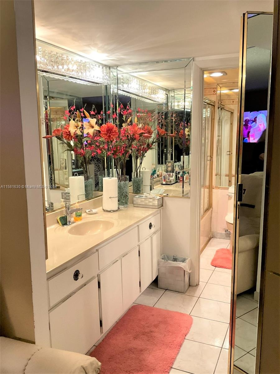 A bathroom features a white vanity, a large mirror, and a pink rug on tile flooring — 4675 W 18th Ct # 502, Hialeah FL 33012, HIALEAH, FL