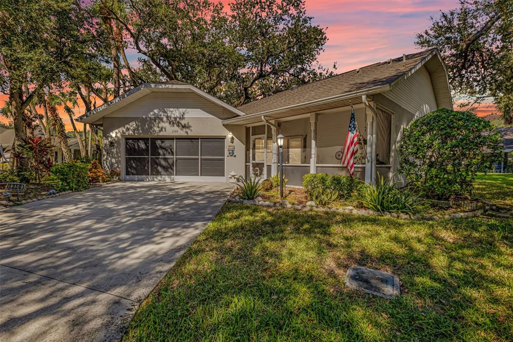 A single-story house with a garage, a screened front porch, and an American flag — 1350 OLD OAK TRAIL, PORT CHARLOTTE, FL