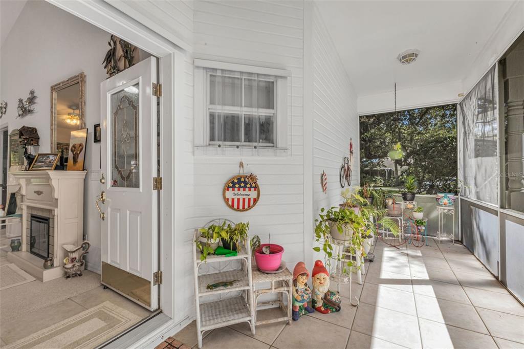 A covered porch features white siding, a front door, potted plants, and two garden gnomes — 1350 OLD OAK TRAIL, PORT CHARLOTTE, FL