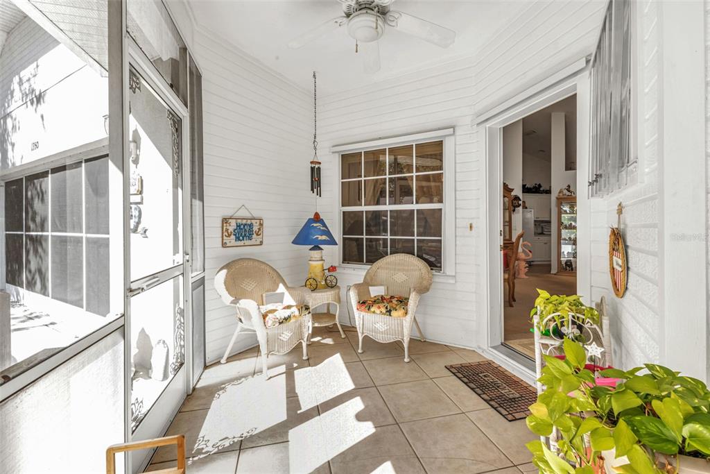 A screened-in porch features white wicker chairs, tile flooring, and a ceiling fan — 1350 OLD OAK TRAIL, PORT CHARLOTTE, FL