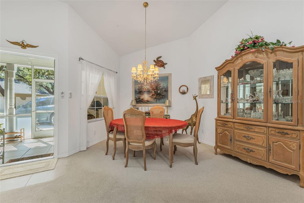 A dining room features a round table with chairs, a crystal chandelier, and a hutch — 1350 OLD OAK TRAIL, PORT CHARLOTTE, FL