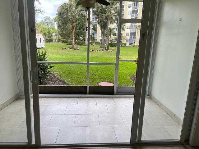 A screened-in patio with light tile flooring overlooks a grassy lawn and apartment buildings — 2731 NE 14th St Causeway NE # 103, Pompano Beach FL 33062, POMPANO BEACH, FL