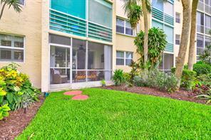 A ground-floor apartment features a screened-in patio overlooking a grassy lawn and palm trees — 2731 NE 14th St Causeway NE # 103, Pompano Beach FL 33062, POMPANO BEACH, FL