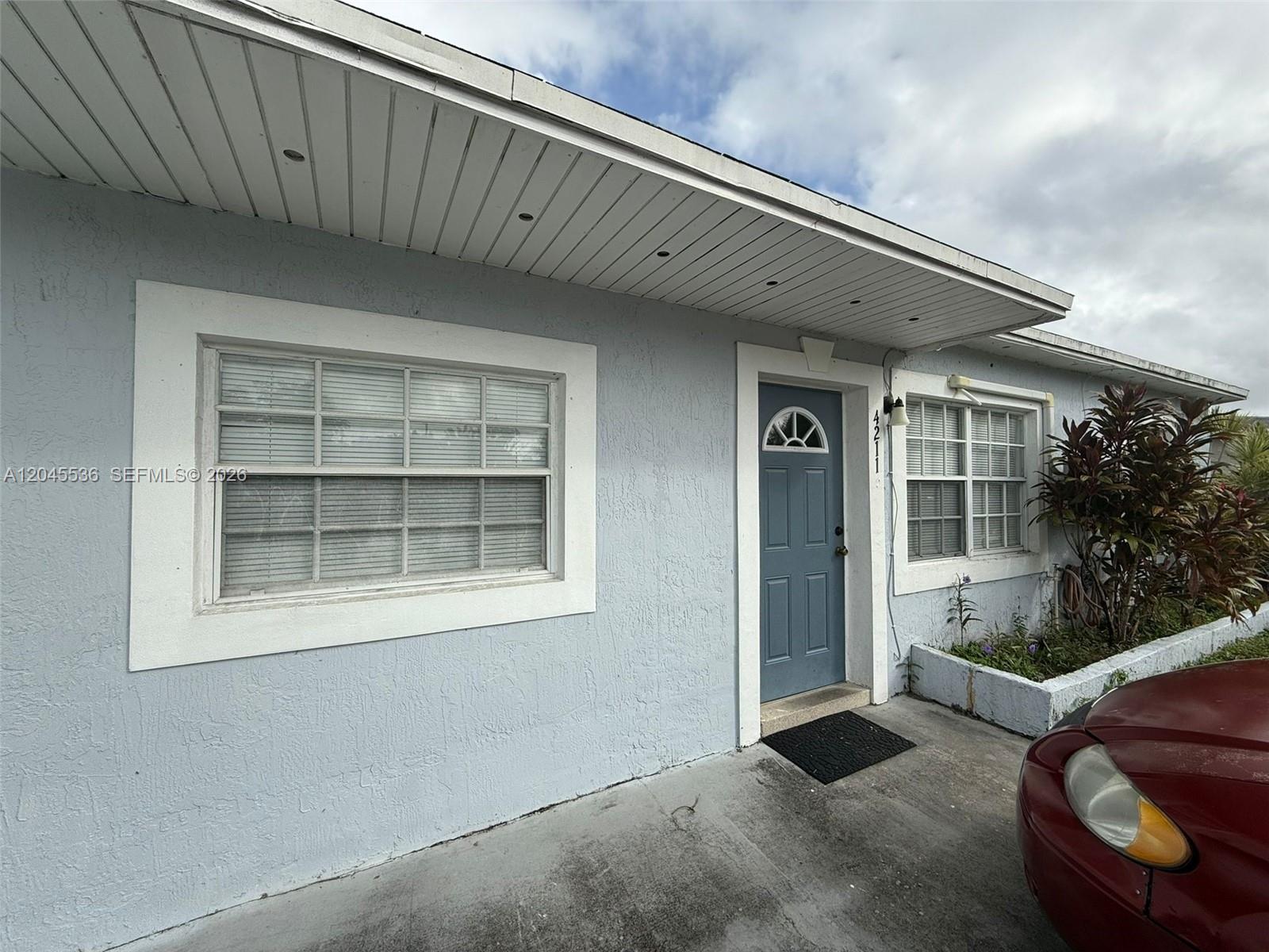 A light blue house exterior features a front door, two windows, and a concrete driveway — 4211 SW 38th St, West Park FL 33023, WEST PARK, FL