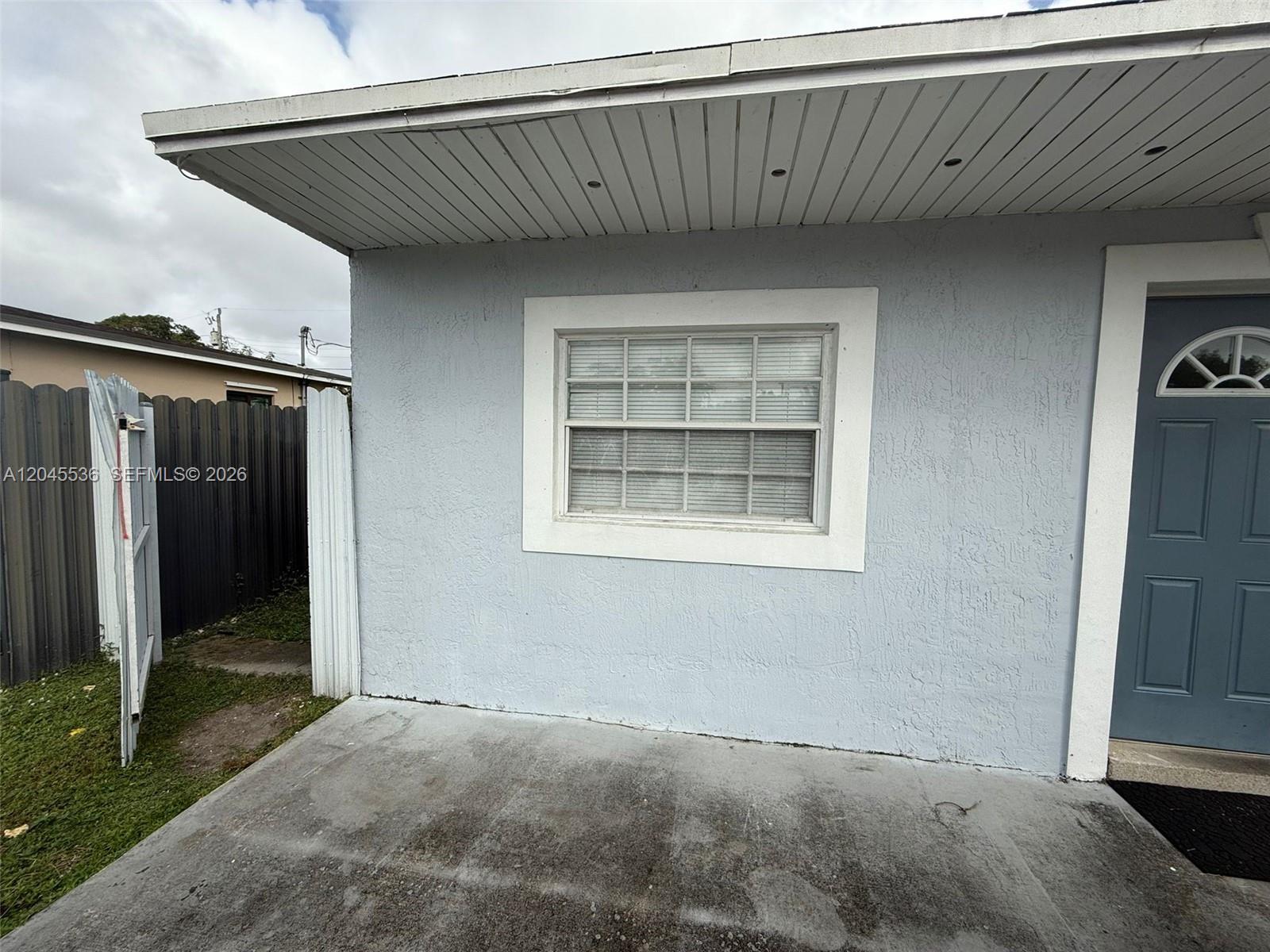 A light blue exterior wall features a single window and a dark blue front door — 4211 SW 38th St, West Park FL 33023, WEST PARK, FL