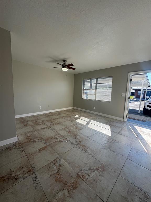 An empty room features light-colored walls, a ceiling fan, and large, mottled floor tiles — 24862 US HIGHWAY 19 N UNIT 2105, CLEARWATER, FL