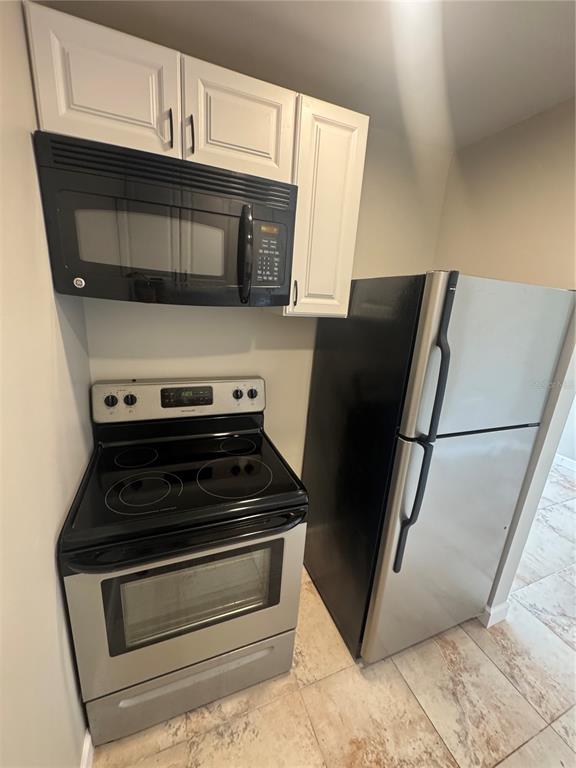 A kitchen area features white cabinets, a black microwave, a stainless stove, and a refrigerator — 24862 US HIGHWAY 19 N UNIT 2105, CLEARWATER, FL
