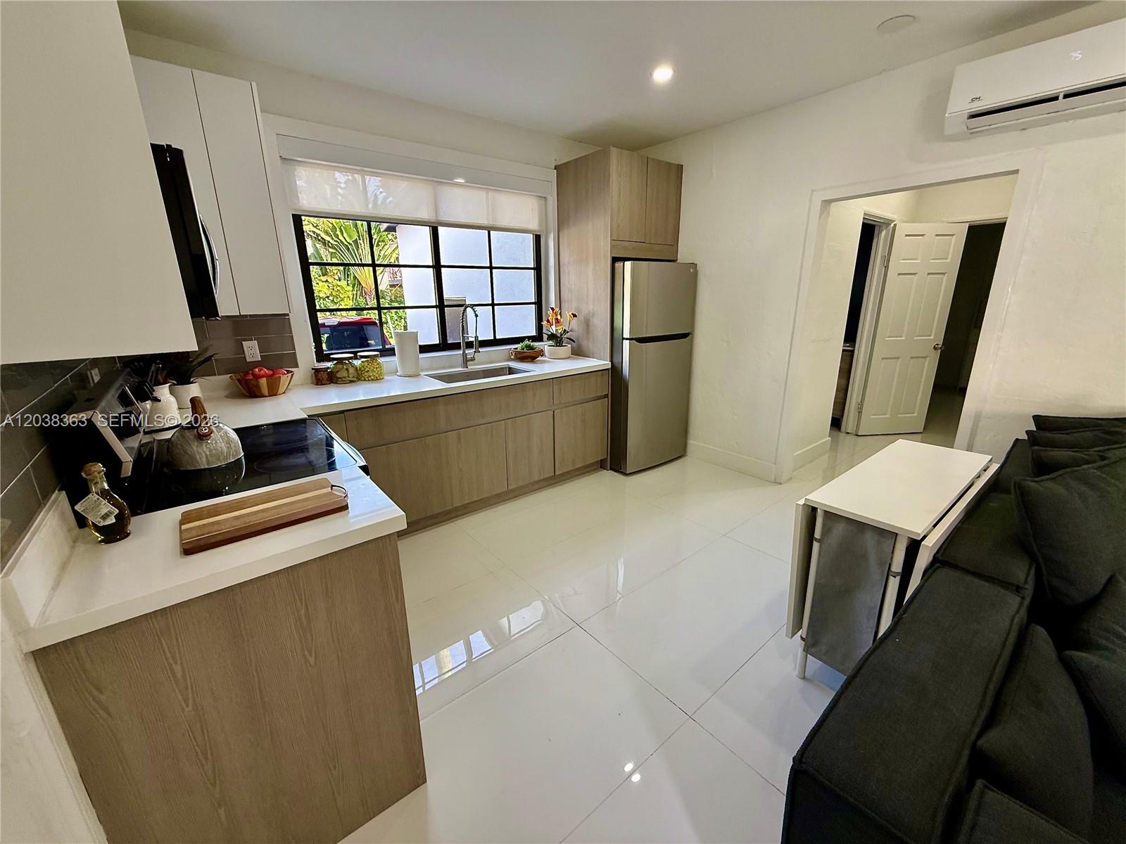 A kitchen features light wood cabinetry, white countertops, stainless steel appliances, and white tile flooring — 733 Michigan Ave # 9, Miami Beach FL 33139, MIAMI BEACH, FL