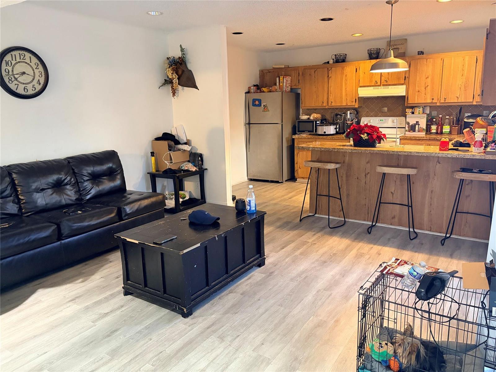 A living room with a black sofa and coffee table opens into a wood-cabinet kitchen — 8208 SW 23 # 18B, North Lauderdale FL, NORTH LAUDERDALE, FL