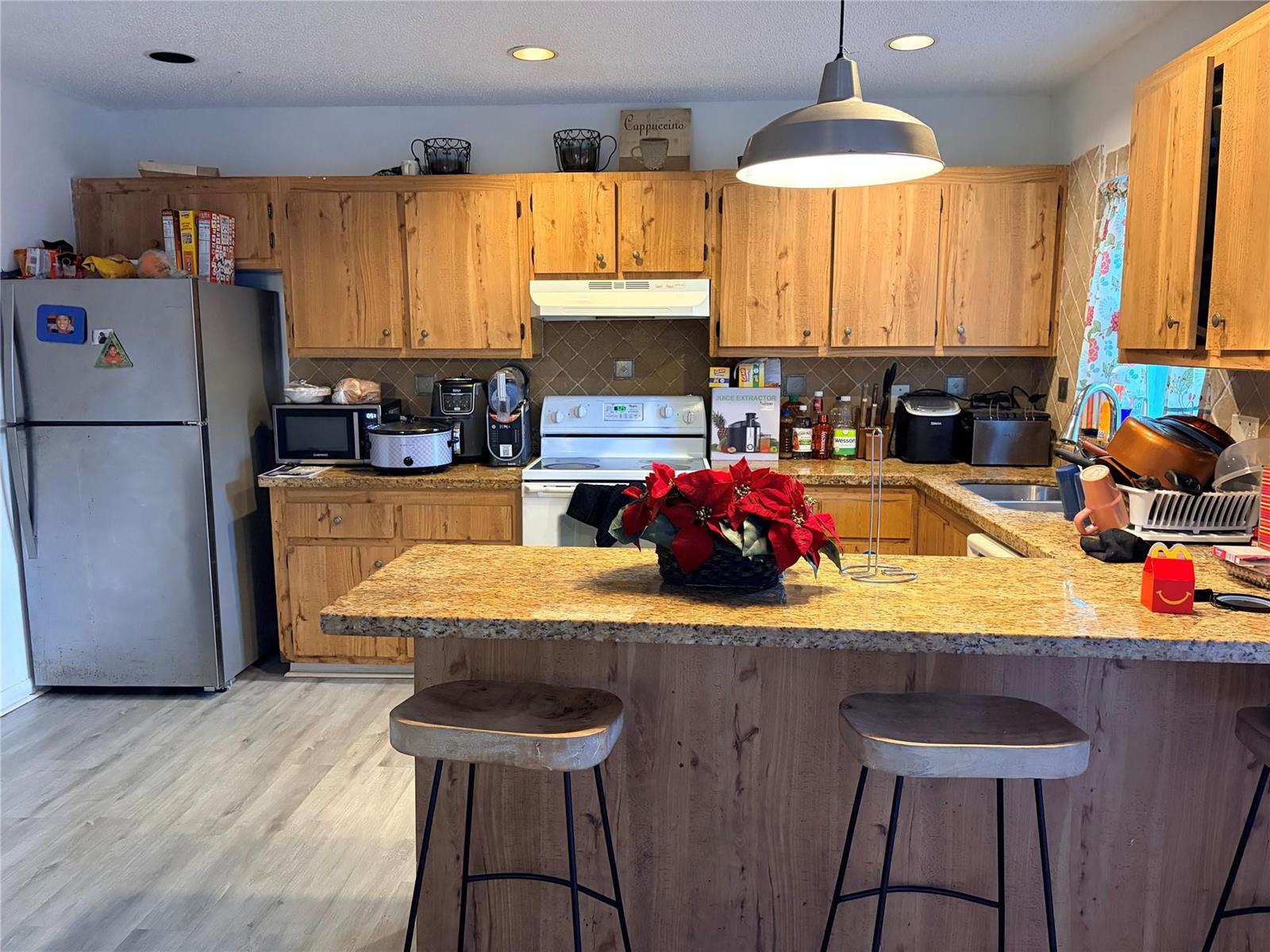 A kitchen features wood cabinets, granite countertops, a breakfast bar with stools, and stainless appliances — 8208 SW 23 # 18B, North Lauderdale FL, NORTH LAUDERDALE, FL