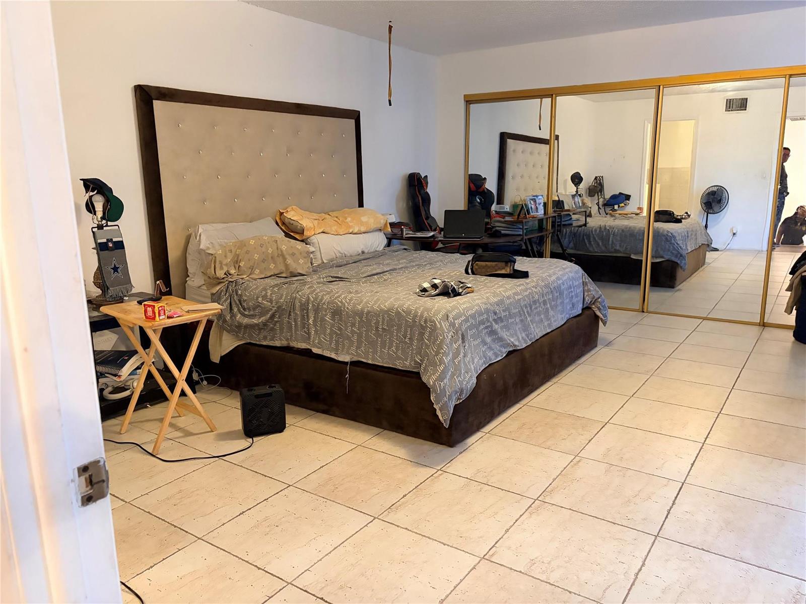 A bedroom features a tufted headboard, a bed with gray bedding, and large mirrored closets — 8208 SW 23 # 18B, North Lauderdale FL, NORTH LAUDERDALE, FL