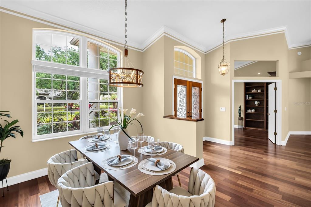 A dining room with a wooden table, upholstered chairs, large windows, and dark wood flooring — 1404 EAST LAKE WOODLANDS PARKWAY, OLDSMAR, FL