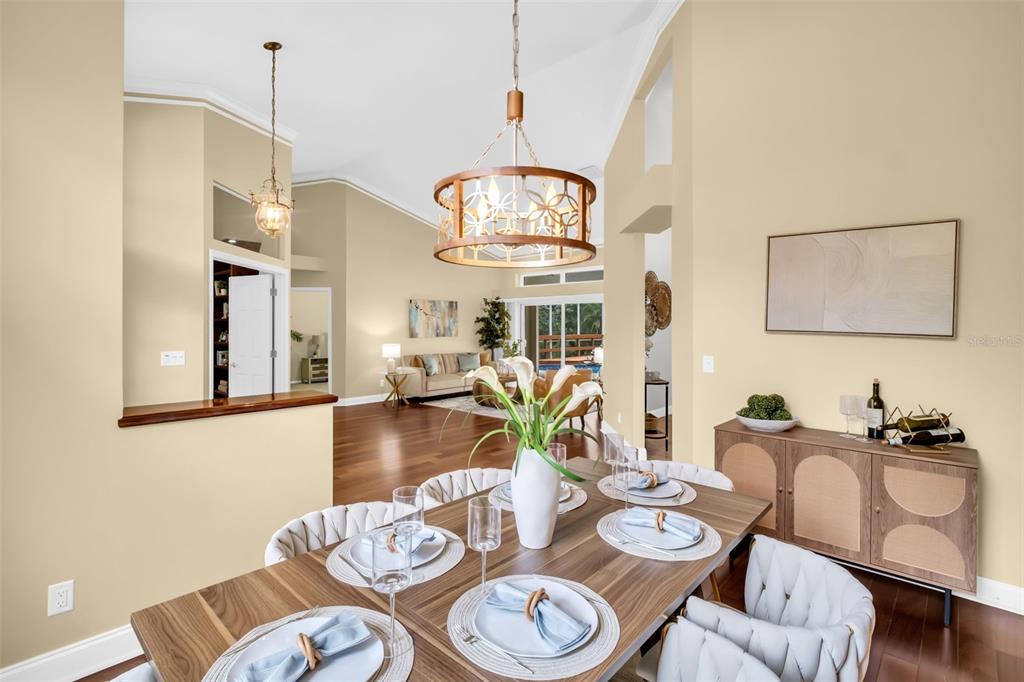 A dining room with a wooden table, chandelier, and an open view into the living area — 1404 EAST LAKE WOODLANDS PARKWAY, OLDSMAR, FL